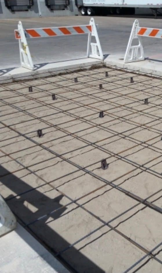 Reinforcing steel set on chairs for a concrete pad replacement beside truck loading docks