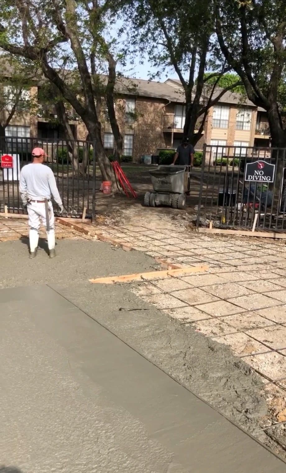 Concrete being placed for a pool deck inside the fenced pool area of an apartment community