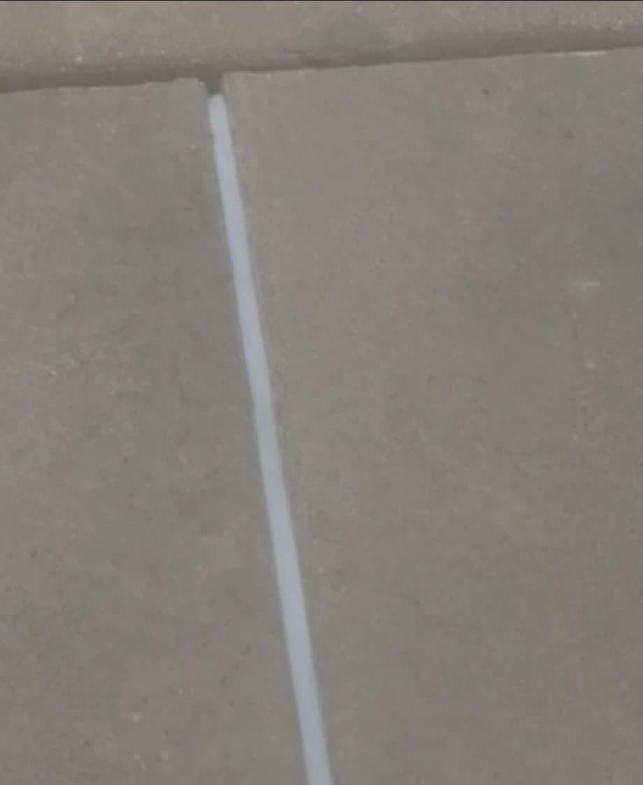 Close view of a newly sealed joint between two concrete sidewalk panels